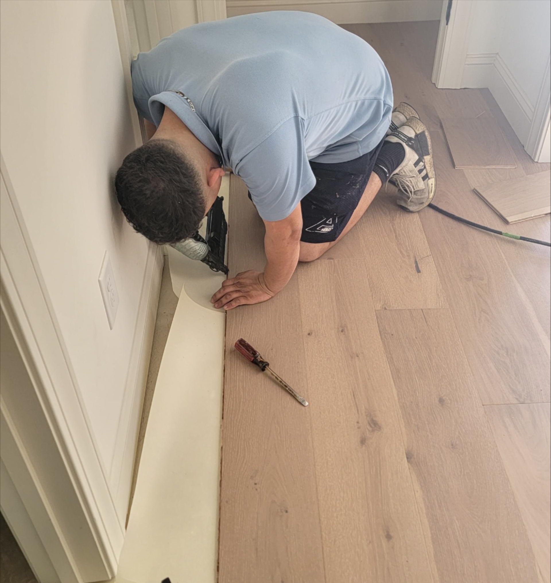 Flooring professional installing a light wood floor