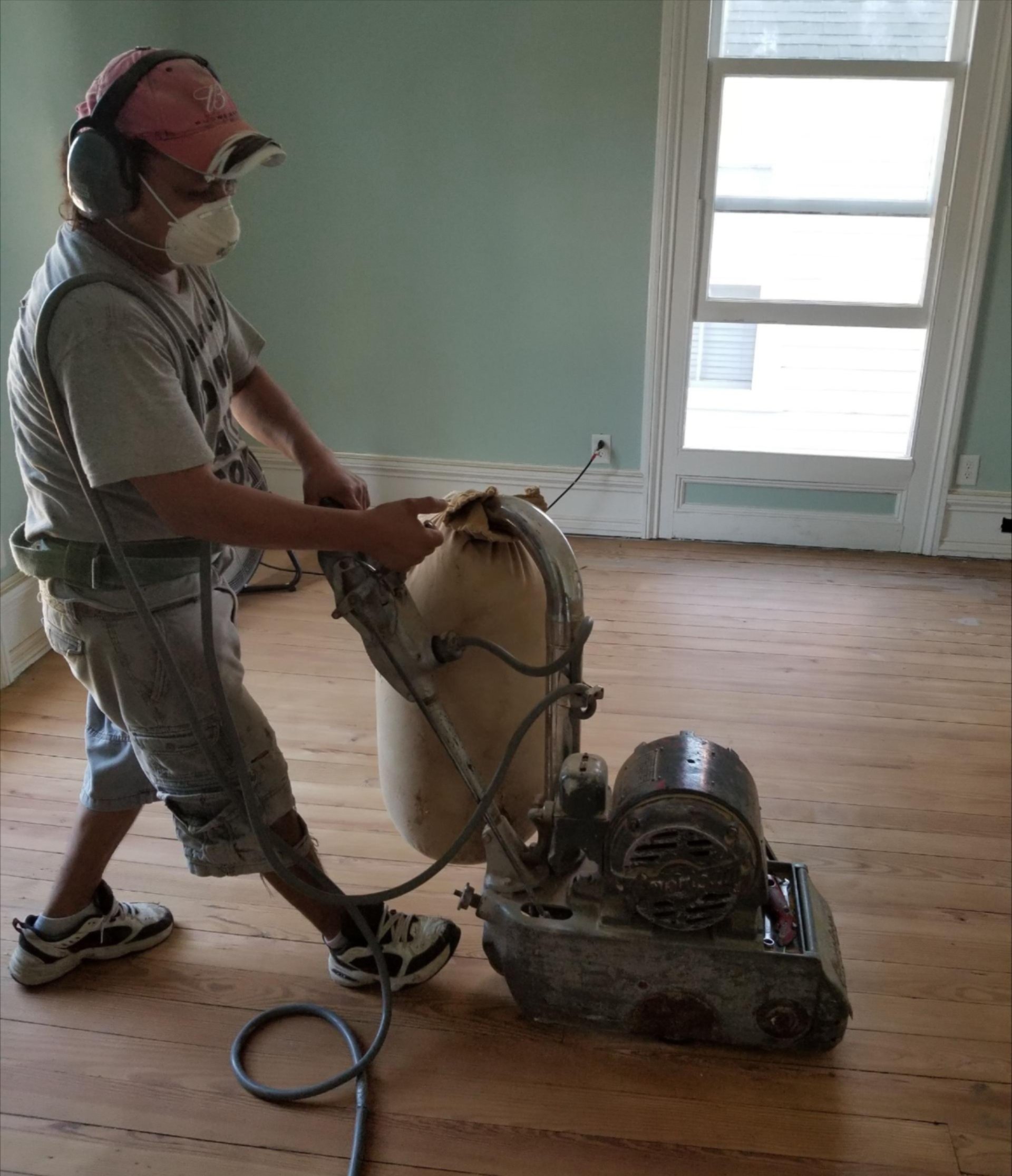 Professional refinishing a hardwood floor with a sanding machine